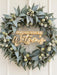 Christmas wreath sign reading Christmas with the Watson's in white and gold mirror acrylic, inside a gum leaf wreath on a door