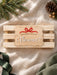 Scalloped wooden name plaque with a red bow reading Special Christmas Delivery For Florence, shown at an angle on a crate