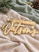 Close up of the gold mirror and white script lettering on the layered family name sign