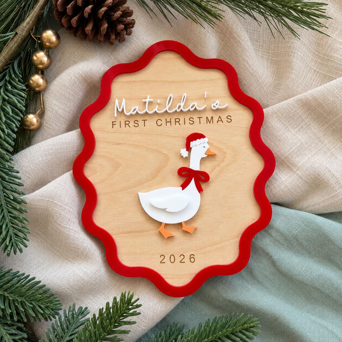 First Christmas sign with Matilda in white acrylic, a goose in a Santa hat and a red wavy border on natural timber