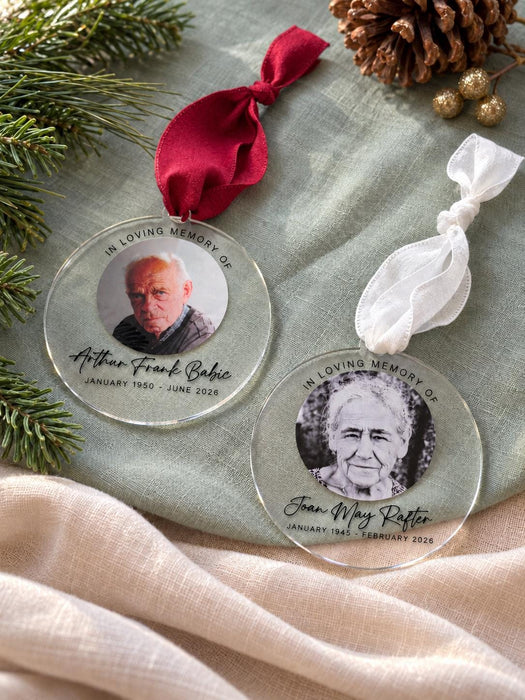 Two clear acrylic memorial baubles side by side, one on a red ribbon and one on a white ribbon