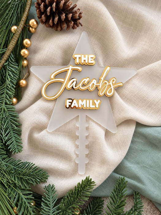 Frosted acrylic family name star with its notched stick, styled with pine branches and gold baubles