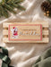 Wooden elf name plaque reading A special delivery for Matilda, shown straight on against a wooden crate