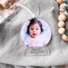 A baby poking out her tongue captured in a photo that has been used to create a unique personalised Christmas decoration. Writing at the base of the bauble says Amelia's First Christmas 2021